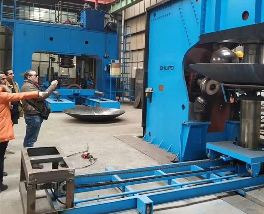 Engineers at a production site next to a dish end press.